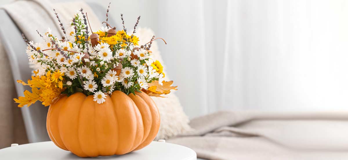 zucca scavato per un bel vaso con fiori sul tavolo