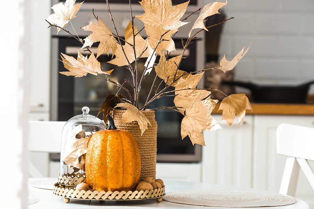 centrotavola con zucca con glitter e vaso con foglie secche